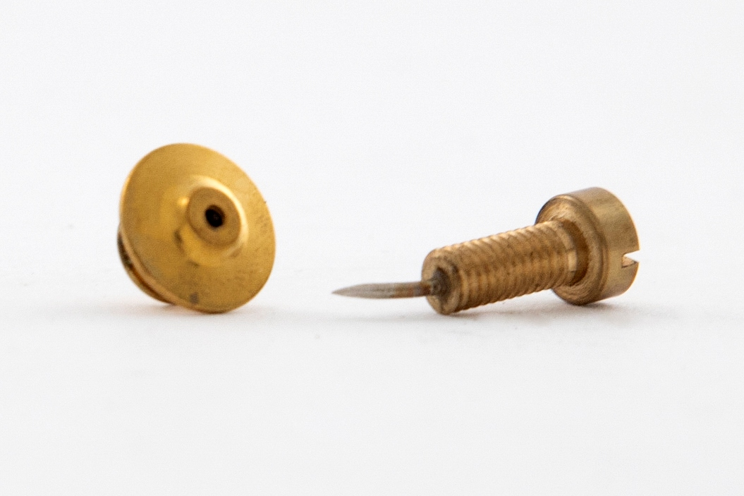 Smykke i eske med bok og folder. En kvadratisk svart eske inneholder et smykke, en bok og en folder. 

Esken har en opptrekksnøkkel preget på lokket.
Smykket er en forgylt pin i form av en skrue. Det er festet på innsiden av lokket.
Bokenhar svart pappbind med "Sigurd Bronger" preget på forsiden. Den har 103 sider, norsk og engelsk tekst, farge- og svart-hvit fotos.
Folderen er i tynn, gråmelert kartong med en opptrekksnøkkel tegnet på forsiden. Den inneholder Sigurd Brongers CV.