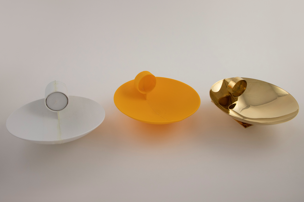 Vegglampe i messing. Rund parabolformet skive med telysholder foran. Rektangulært feste på baksiden med en avstandsplate mellom feste og parabol. Designet tar opp i seg den pre-elektriske lampetypen med reflektorskjerm. 

To 3D-printede prototyper i plast. En hvit prototyp for en bordversjon av lampen, som har en rund parabol festet til en høy sylinder. Sylinderen fungerer som både fot og telysholder. Grønt kitt under basen.
 
Gul prototyp for vegglampen. Samme utforming som messinglampen, men har ikke rektangulært feste med avstandsplate på samme måten. Avstandsplaten på prototypen er festet på nedre halvdel av parabolen, og veggfestet er festet direkte på parabolen.