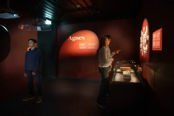 Tre ungdommer studerer en utstilling der ulike felt på en oransje vegg er opplyst.