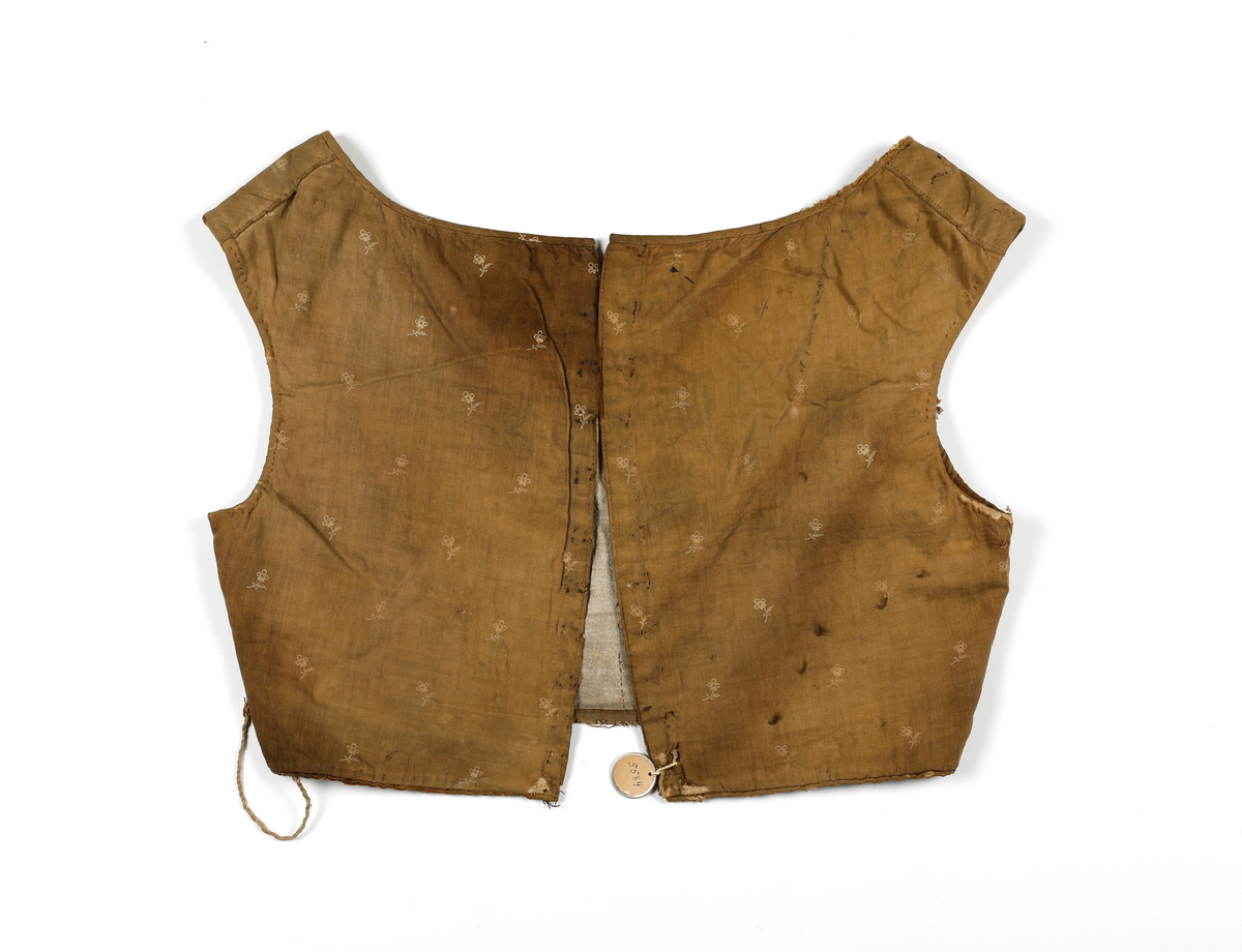 Kjoleliv som er fôret og hektes sammen i ryggen. Fôret er av lin og ellers er livet av bomull. Det er lagt inn snor i folden i nedkant og i front (passe poilerte kanter). Skjørtet har vært festet i livet, men er sprettet av. Livet har hatt 11 hekter, som nå er fjernet, og trådrester sitter igjen etter disse. 