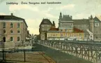 Östra Storgatan i Jönköping vid hamnkanalen. Till vänster om bron ligger Bankaktiebolaget Södra Sverige och i huset till höger Konfektions AB Norden och Cigarr och Tobakshandel. Vykort skrivet 1911-06-28.