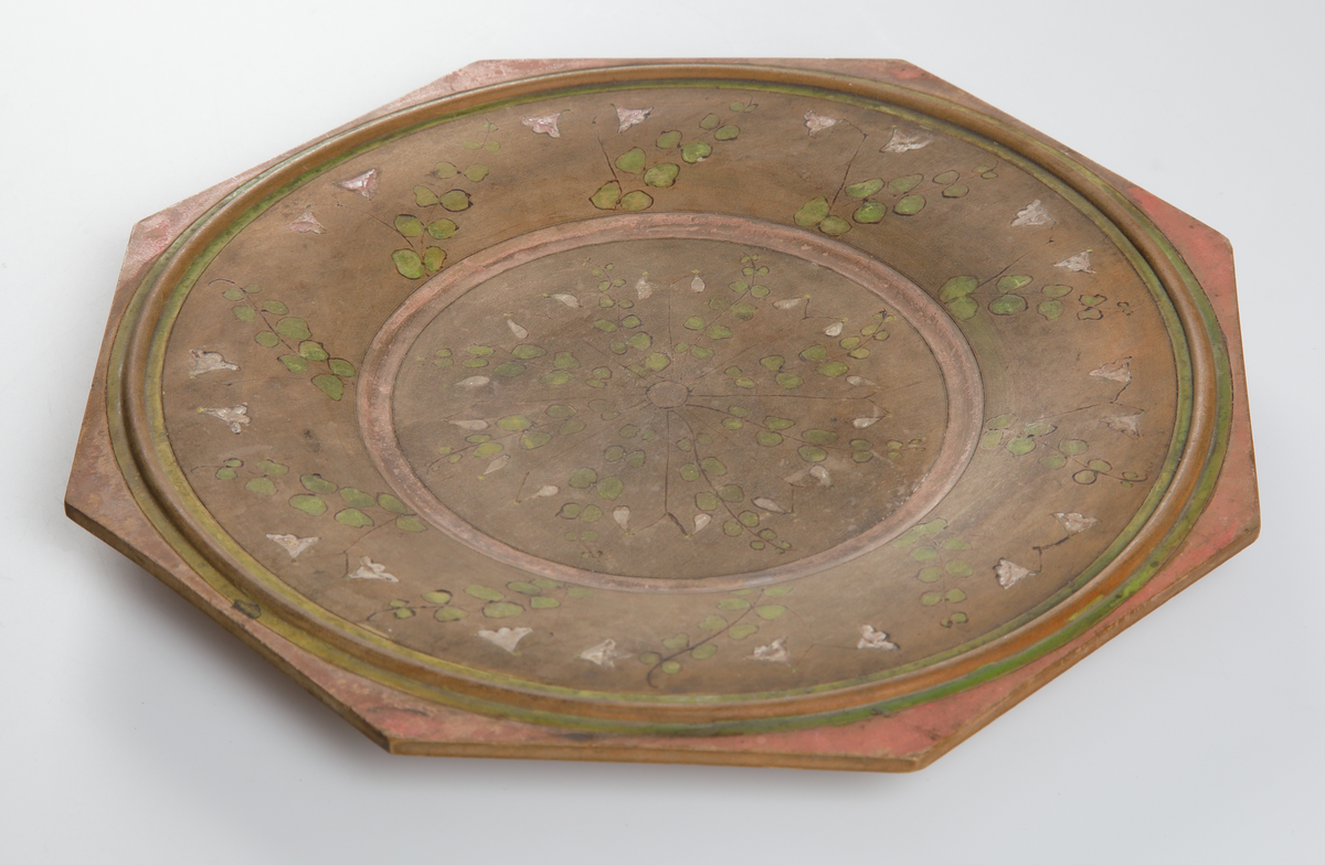 Trätallrik, åttkantig med glödritad och målad dekor i form av linnéor.

Inskrivet i huvudkatalog 1932.