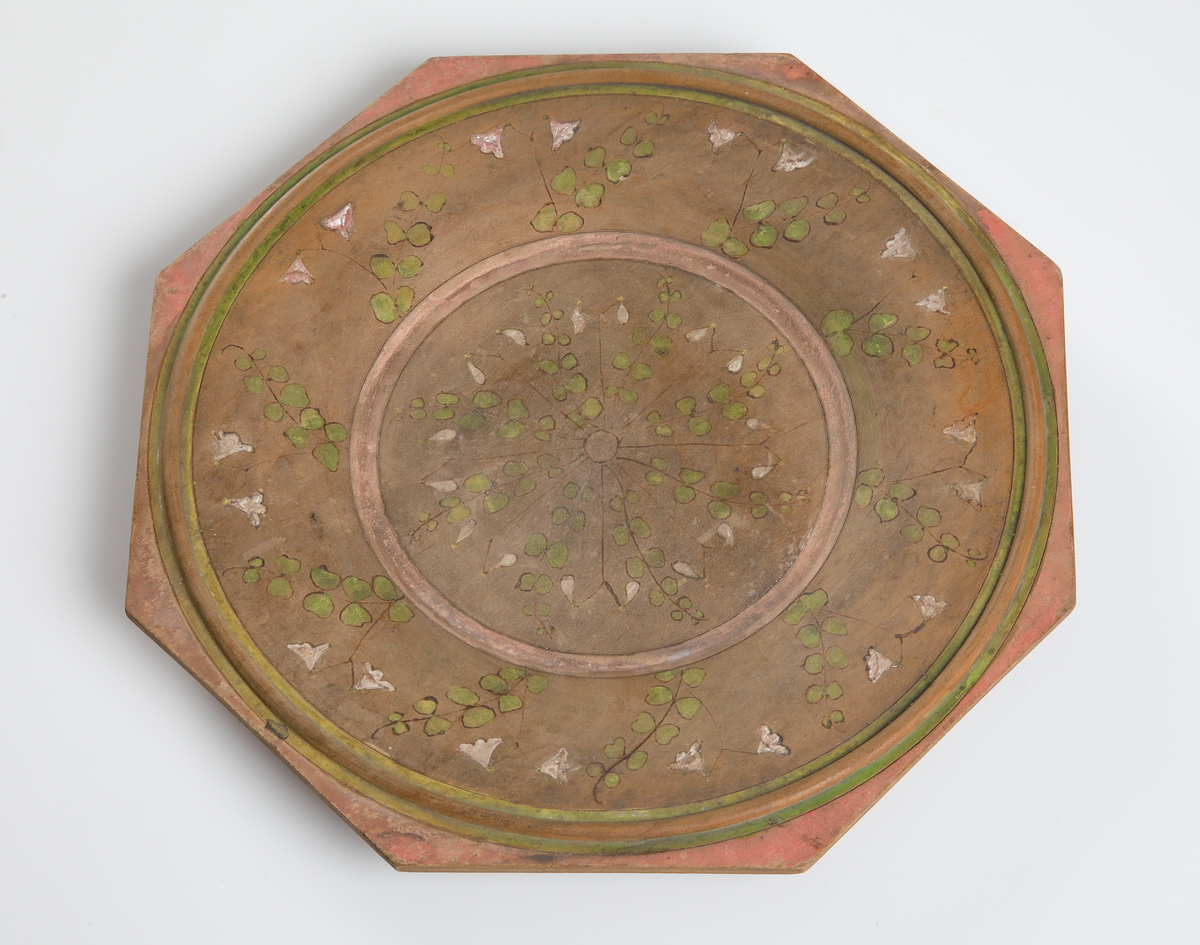 Trätallrik, åttkantig med glödritad och målad dekor i form av linnéor.

Inskrivet i huvudkatalog 1932.