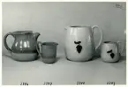 Tre kannor och en mugg från Bo Fajans, formgivare Eva Jancke-Björk, 1900-talets mitt. Kannan och muggen till höger i bild har en relief som dekor.