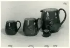 Tre muggar och en kanna med reliefdekor från Bo Fajans, formgivare Eva Jancke-Björk, 1900-talets mitt.