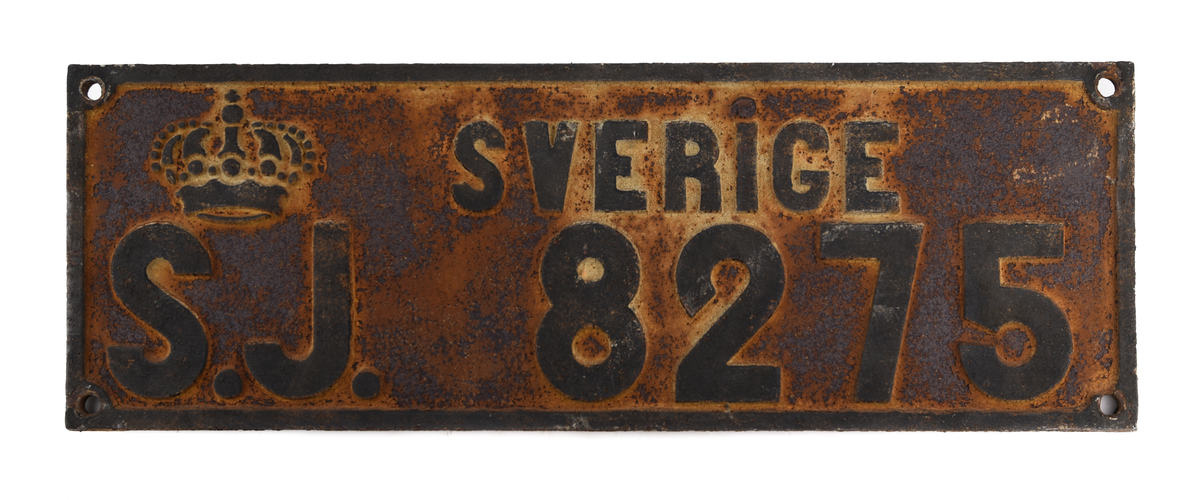 Två stycken rektangulära skyltar av gjutjärn med svart text på vit botten: "SVERIGE S.J. 8275". Mycket rostig.
Från godsvagn.