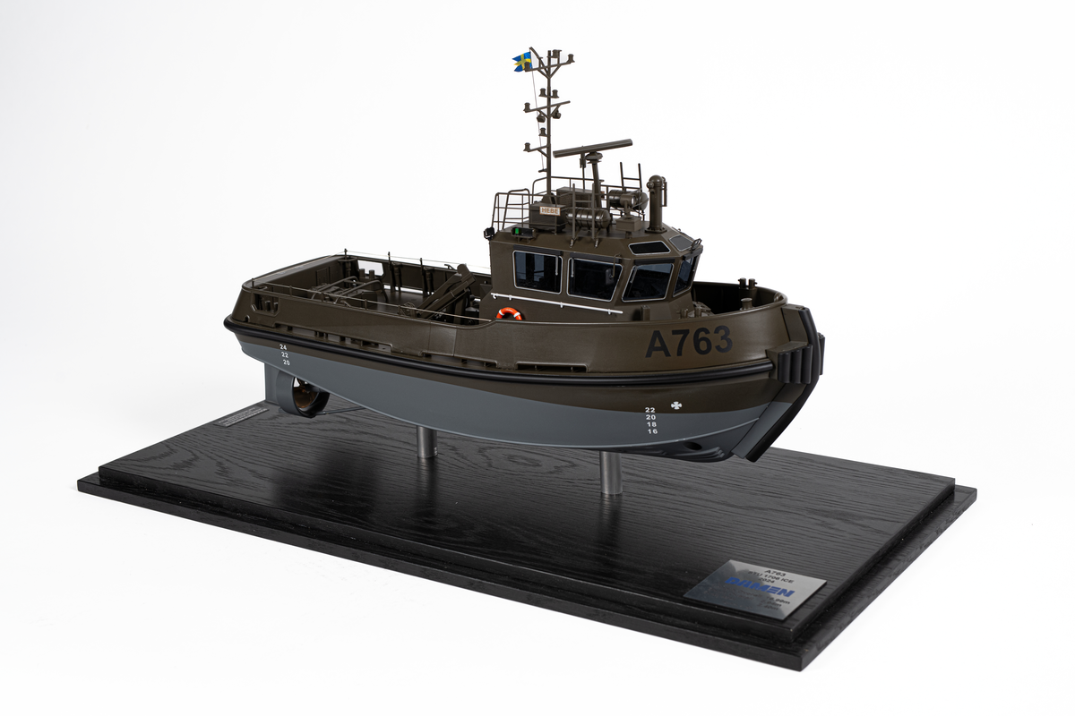 Fartygsmodell föreställande hamnbogseraren Hebe. Modell av metall och plast på två stöd. Monterbotten av mörkt trä samt plexiglashuv. Fartygsskrovet gråmålat under vattenlinjen samt militärgrönt upptill. Märkt i svart: "A763". Baktill en lyftkran. Namnbrädor som anger att det är Hebe.

En skylt som anger tillverkare: "Scale modells Weston ltd". En skylt som anger mått samt texten: "A763 STU 1706 ICE DAMEN 2024".