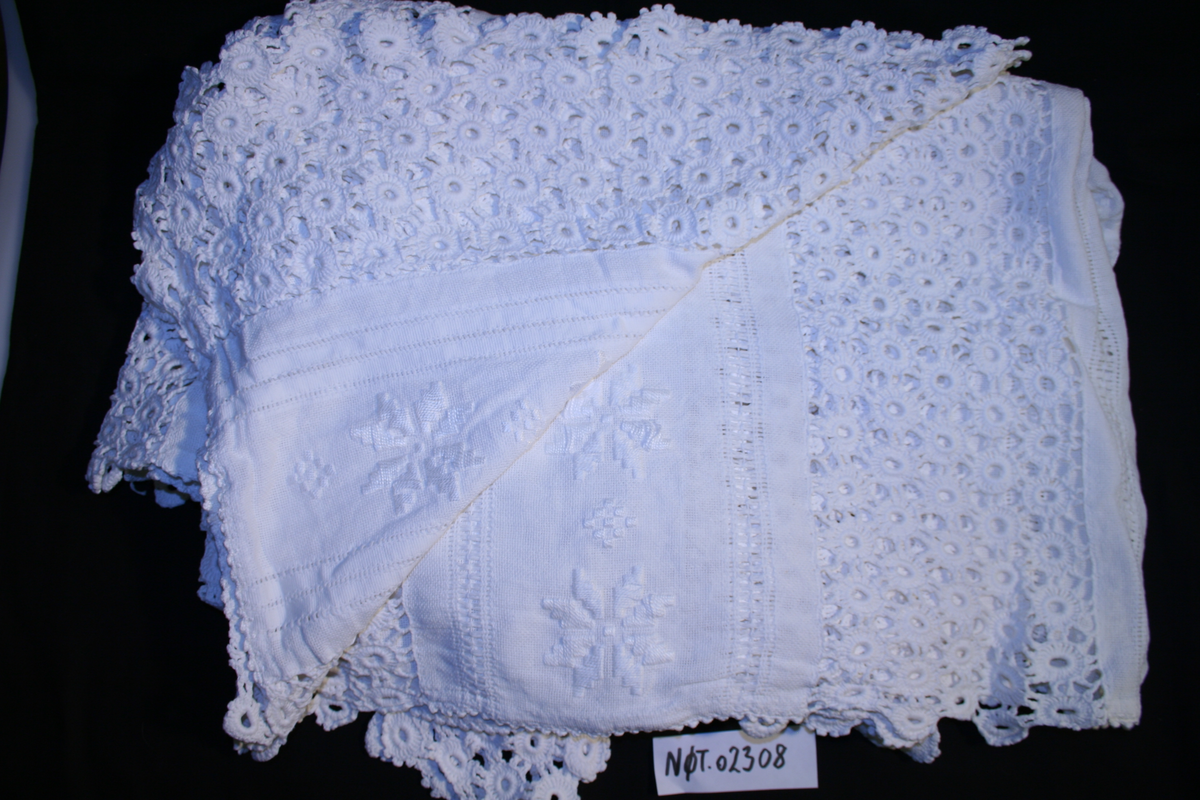 Teppet er satt sammen av hekla partier og stoffstykker med åttebladsroser påbrodert. Sengeteppet var gevinst på basar i ei kvinneforening på Kirkeegga ca. 1930.