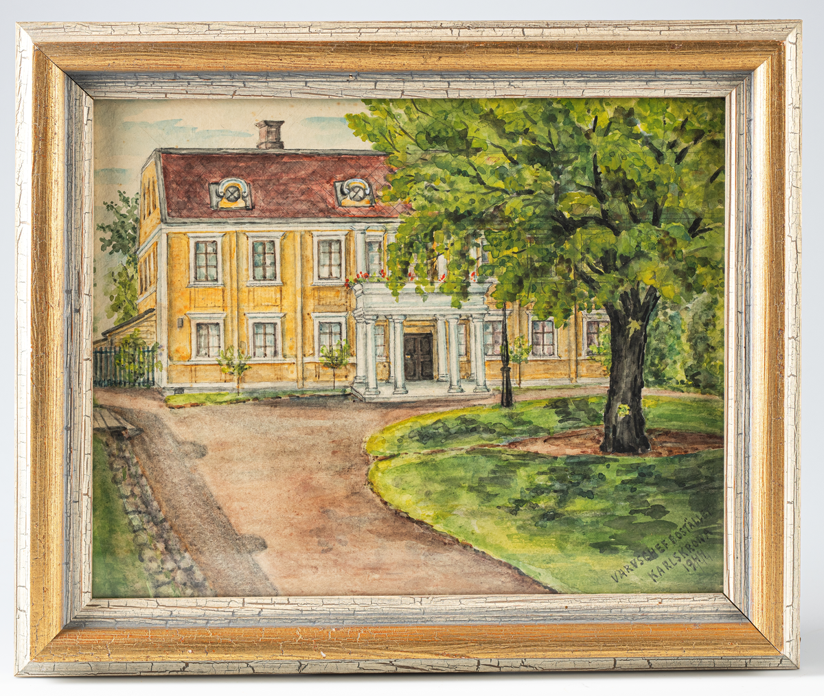 Akvarell inom glas och ram, liggande format visande Varvschefsbostället, Karlskrona. Tvåvåningshus av gulmålat trä, spröjsade fönster, mansardtak med små fönster samt en kolonnportik framför entrén som bär upp en balkong på ovanvåningen. I förgrunden grusgång samt gräsmatta med ett stort lövträd. Text i höger, nedre hörn:" VARVSCHEFSBOSTÄLLET KARLSKRONA 1944 ". Motivet är naturtroget återgivet i mild färgton.
Tavlan är inom glas och ram av trä, B = 36 mm, profilerad och målad i vitt samt guld.
Konstnär : Gunnil Bergström 1869 - 1952.
Net.nr A 770  1:12