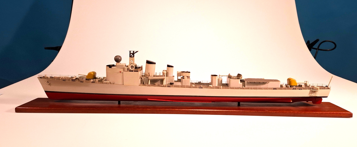 Fartygsmodell, huvudsaklingen gjord av trä med detaljer i plast och metall. Fartyget föreställer med högsta sannolikhet fregatten Sundsvall (1965-1982), tidigare stadsjagare (1942-1965). Modellen är målad grå över vattenlinjen, med en avskiljande svart linje och en röd bottenfärg. På fördäck står en kanon som är bemålad i gulaktig grön färg. På akterdäck finns en likadan kanon. Det finns två skorstenar med svarta toppar och ovanför styrhytten finns en ställning med grå botten och svart överkant som är trasig i toppen. I akterdelen finns en helikopterplatta och fartyget har tidigare haft två propellrar varav propellern på vänster sida är borta. Runt däcket finns en reling tillverkad i metall som omger hela fartyget. Modellen står på en fernissad platta av trä med hjälp av två kraftiga skruvar.