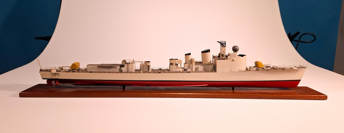 Fartygsmodell, huvudsaklingen gjord av trä med detaljer i plast och metall. Fartyget föreställer med högsta sannolikhet fregatten Sundsvall (1965-1982), tidigare stadsjagare (1942-1965). Modellen är målad grå över vattenlinjen, med en avskiljande svart linje och en röd bottenfärg. På fördäck står en kanon som är bemålad i gulaktig grön färg. På akterdäck finns en likadan kanon. Det finns två skorstenar med svarta toppar och ovanför styrhytten finns en ställning med grå botten och svart överkant som är trasig i toppen. I akterdelen finns en helikopterplatta och fartyget har tidigare haft två propellrar varav propellern på vänster sida är borta. Runt däcket finns en reling tillverkad i metall som omger hela fartyget. Modellen står på en fernissad platta av trä med hjälp av två kraftiga skruvar.