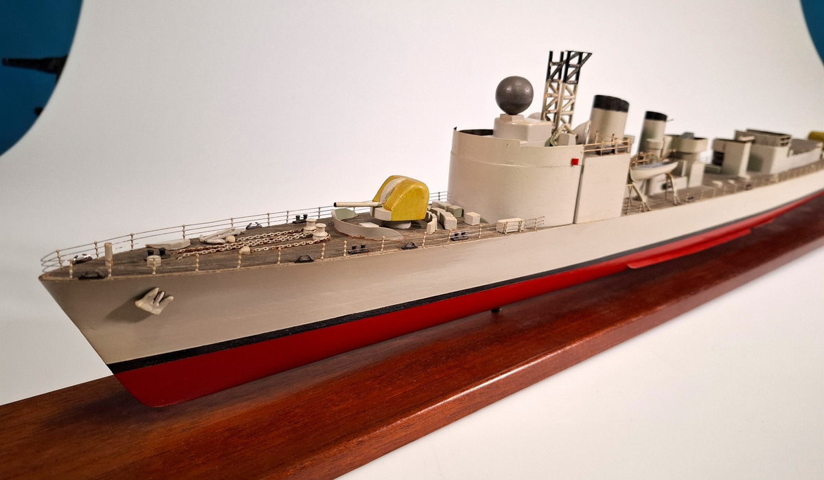 Fartygsmodell, huvudsaklingen gjord av trä med detaljer i plast och metall. Fartyget föreställer med högsta sannolikhet fregatten Sundsvall (1965-1982), tidigare stadsjagare (1942-1965). Modellen är målad grå över vattenlinjen, med en avskiljande svart linje och en röd bottenfärg. På fördäck står en kanon som är bemålad i gulaktig grön färg. På akterdäck finns en likadan kanon. Det finns två skorstenar med svarta toppar och ovanför styrhytten finns en ställning med grå botten och svart överkant som är trasig i toppen. I akterdelen finns en helikopterplatta och fartyget har tidigare haft två propellrar varav propellern på vänster sida är borta. Runt däcket finns en reling tillverkad i metall som omger hela fartyget. Modellen står på en fernissad platta av trä med hjälp av två kraftiga skruvar.