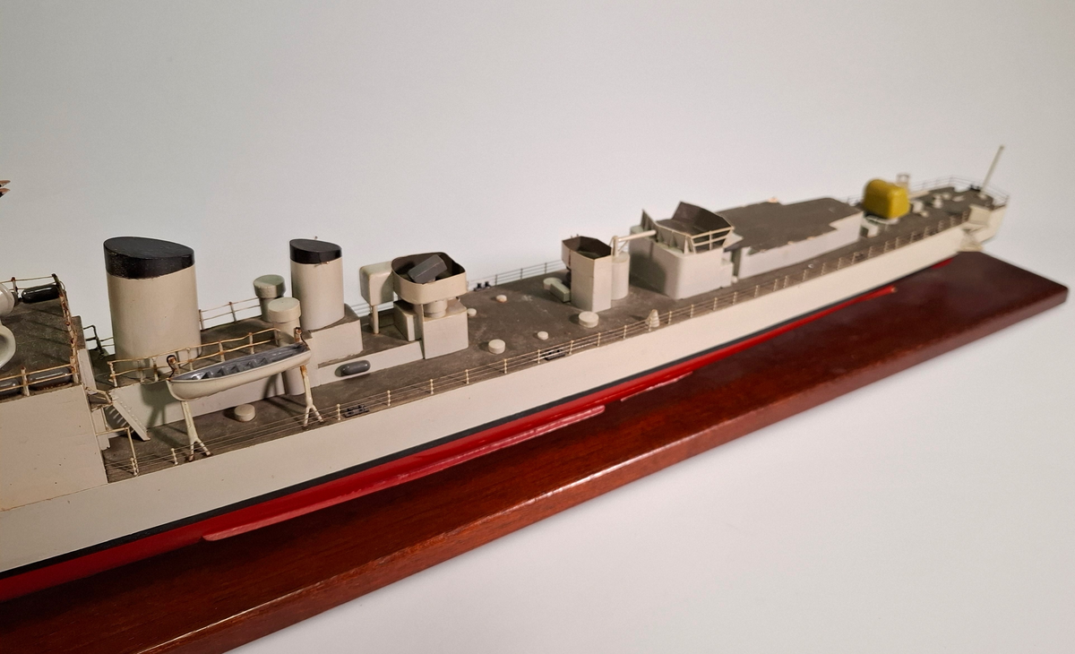 Fartygsmodell, huvudsaklingen gjord av trä med detaljer i plast och metall. Fartyget föreställer med högsta sannolikhet fregatten Sundsvall (1965-1982), tidigare stadsjagare (1942-1965). Modellen är målad grå över vattenlinjen, med en avskiljande svart linje och en röd bottenfärg. På fördäck står en kanon som är bemålad i gulaktig grön färg. På akterdäck finns en likadan kanon. Det finns två skorstenar med svarta toppar och ovanför styrhytten finns en ställning med grå botten och svart överkant som är trasig i toppen. I akterdelen finns en helikopterplatta och fartyget har tidigare haft två propellrar varav propellern på vänster sida är borta. Runt däcket finns en reling tillverkad i metall som omger hela fartyget. Modellen står på en fernissad platta av trä med hjälp av två kraftiga skruvar.