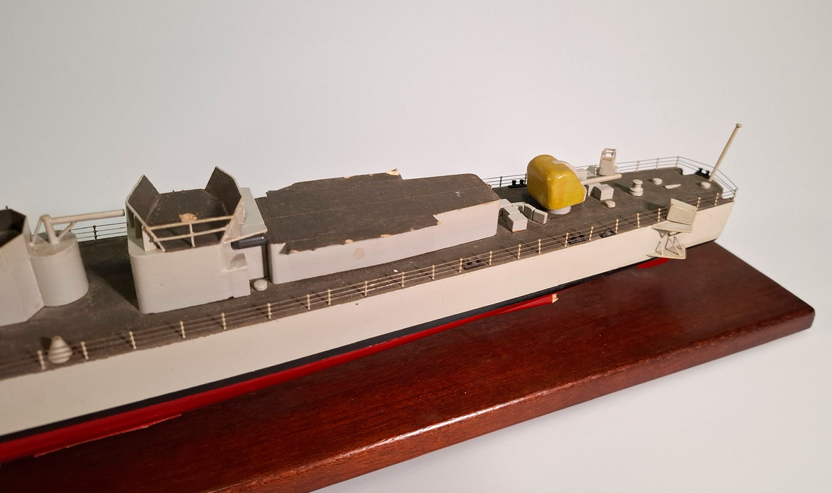 Fartygsmodell, huvudsaklingen gjord av trä med detaljer i plast och metall. Fartyget föreställer med högsta sannolikhet fregatten Sundsvall (1965-1982), tidigare stadsjagare (1942-1965). Modellen är målad grå över vattenlinjen, med en avskiljande svart linje och en röd bottenfärg. På fördäck står en kanon som är bemålad i gulaktig grön färg. På akterdäck finns en likadan kanon. Det finns två skorstenar med svarta toppar och ovanför styrhytten finns en ställning med grå botten och svart överkant som är trasig i toppen. I akterdelen finns en helikopterplatta och fartyget har tidigare haft två propellrar varav propellern på vänster sida är borta. Runt däcket finns en reling tillverkad i metall som omger hela fartyget. Modellen står på en fernissad platta av trä med hjälp av två kraftiga skruvar.