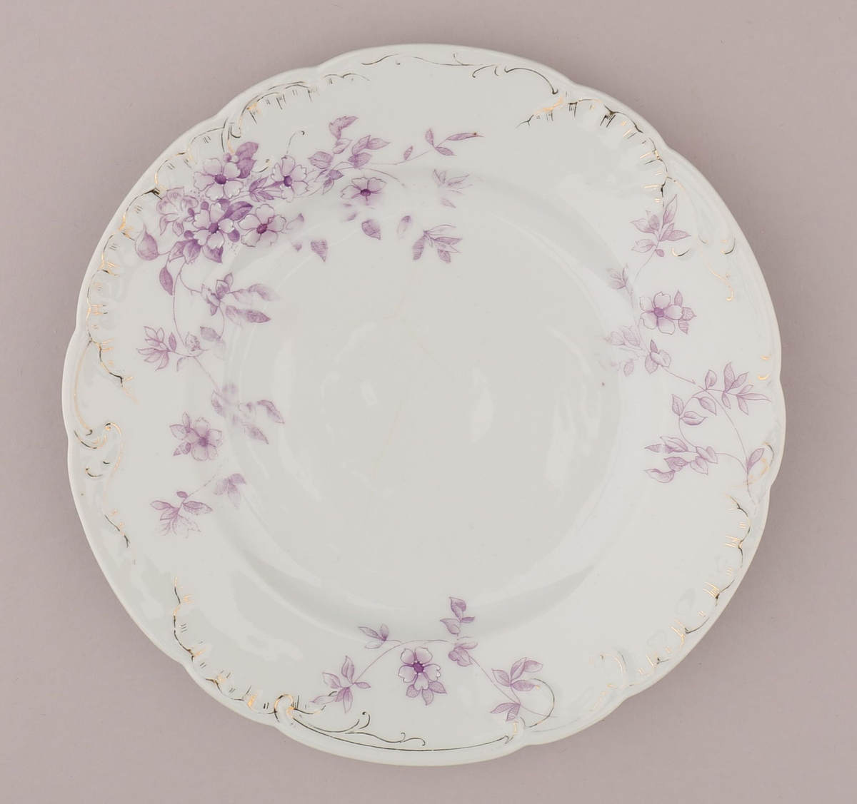 Rocaille og blomstermotiv bestående av blomster, blader, ranker, stengler. Motiv dekorert med tynn strek i fiolett nyanse med skraverte og åpne felt. Mørke fruktknute, lyse kronblader, skraverte blader i forskjellig mønster og alt fra lyse til mørke i fargen. Hvitt pigment benyttet for kontrast nær fruktknuten og ytterst på kronbladene.