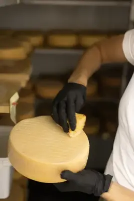 En kvinne vasker over en ost som ligger til lagring. 