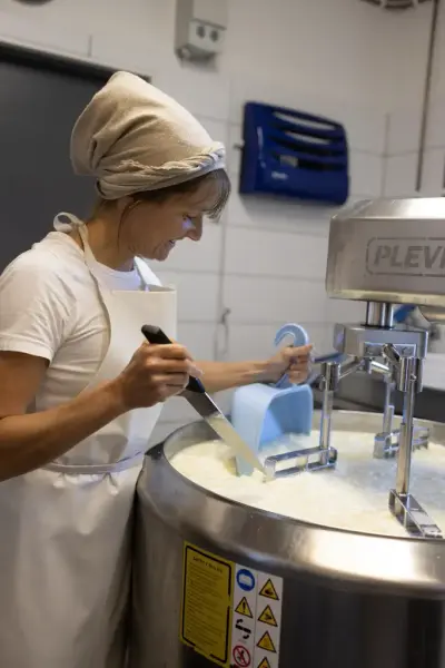 En kvinne holder på å lage ost. 