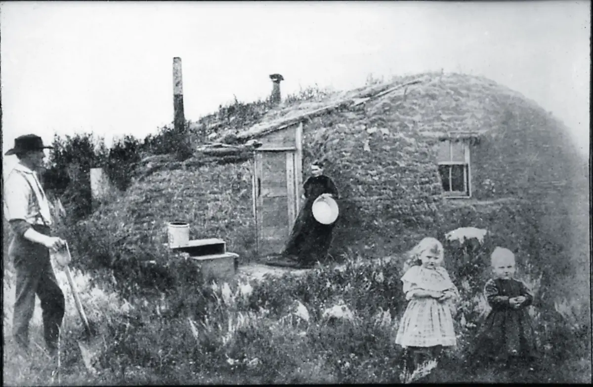 Foto av et torvhus fra 1882. Utenfor ser vi to barn med foreldrene i en arbeidssituasjon