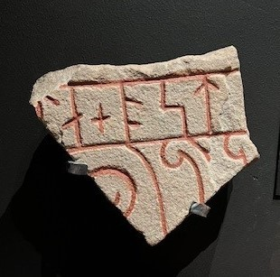 Runstensfragment av sandsten. Kommer från Björke i Hille socken. Den bevarade inskriften lyder: …-a + ost… Före a-runan finns delar av en runa som är antingen L eller T. Ristad av Åsmund Kåresson i mitten av 1000-talet.
Runsten Gs 18, del B.