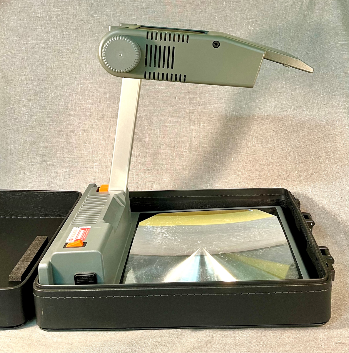 Sammenleggbar projektor oppbevart i trekoffert.