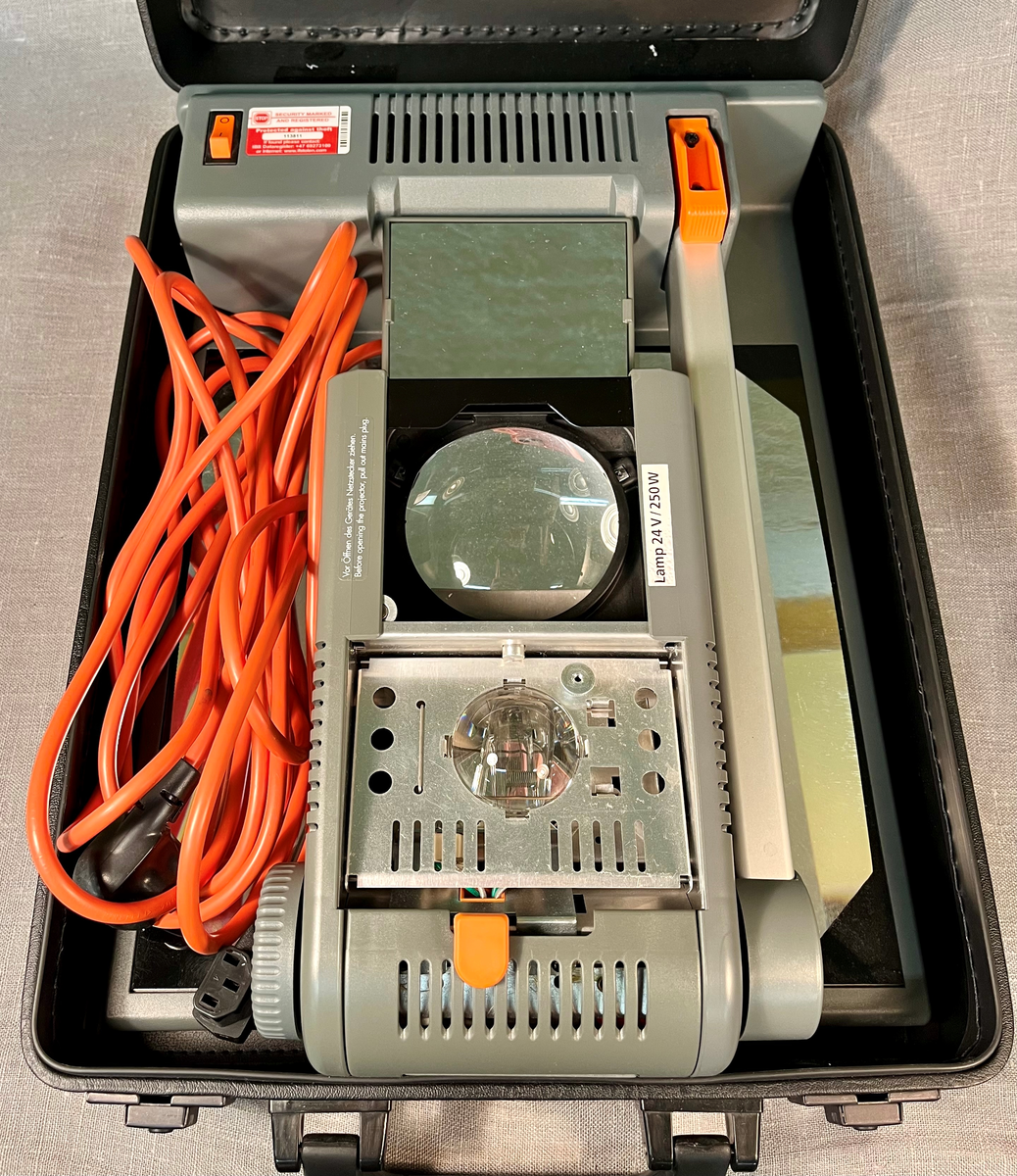 Sammenleggbar projektor oppbevart i trekoffert.