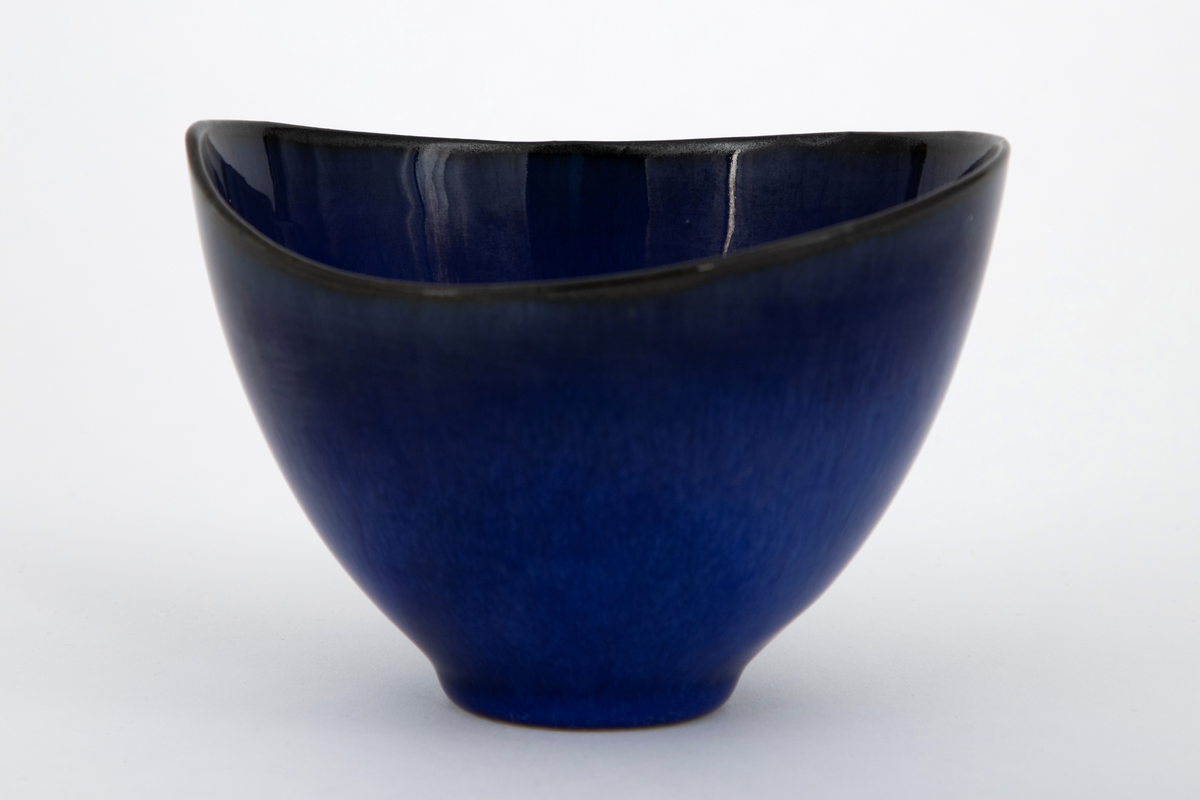 Skål i steingods, oval form med noe skjevt oppsvunget munningsrand i begge ender. Dekket med blank glasur i skiftende nyanser av blått, lysere blå mot bunnen og dypblå nærmere munningsranden.