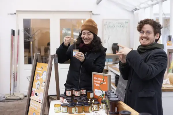 To personer viser frem honning fra våre bigårder på Gartneriet, Dronningparken, Kongsgården, Oscarshall. 