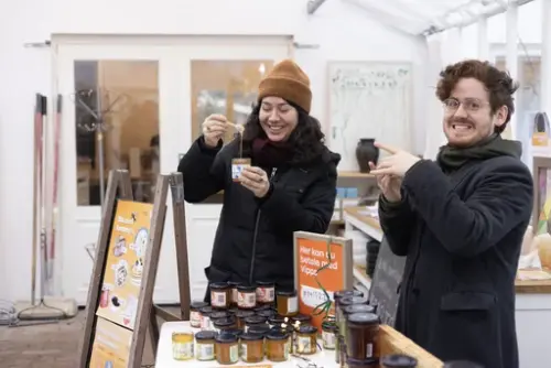 To personer viser frem honning fra våre bigårder på Gartneriet, Dronningparken, Kongsgården, Oscarshall. 