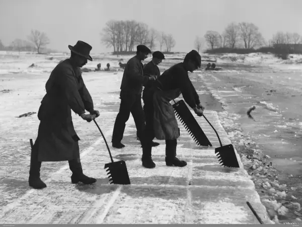 Svart-hvitt bilde av menn som skjærer ut isblokker i Smestaddammen. 