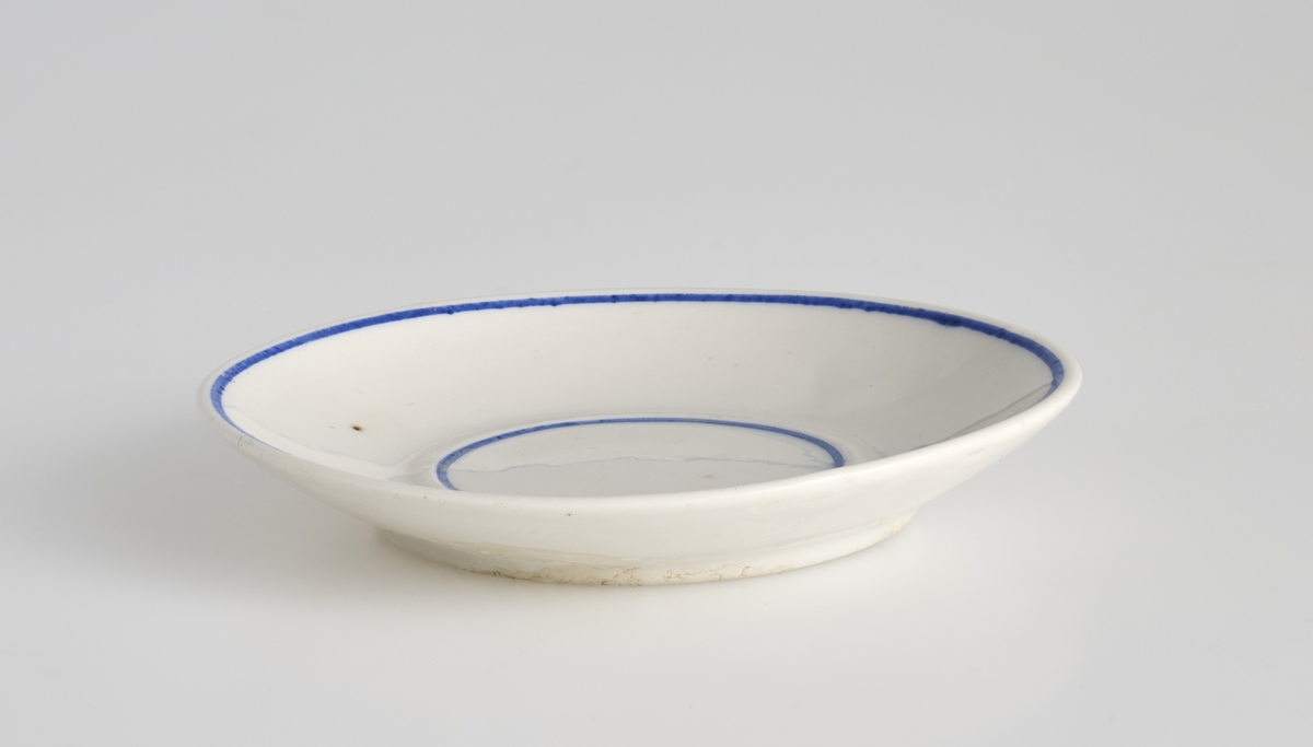 To like tallerkener brukt i lekestue på 1930-tallet. 
Tallerkenene er runde i formen, glasert hvite med blåe linjer langs toppen av kanten og langs fordypningen i midten av tallerkenene. På undersiden løper det en kant som danner en sirkel og utgjør foten av tallerkenene. 
Tallerken 01 er noe større enn 02. Bunnen av tallerken 01 er det gravert inn "3361", mens på tallerken 02 er det gravert inn "1868"