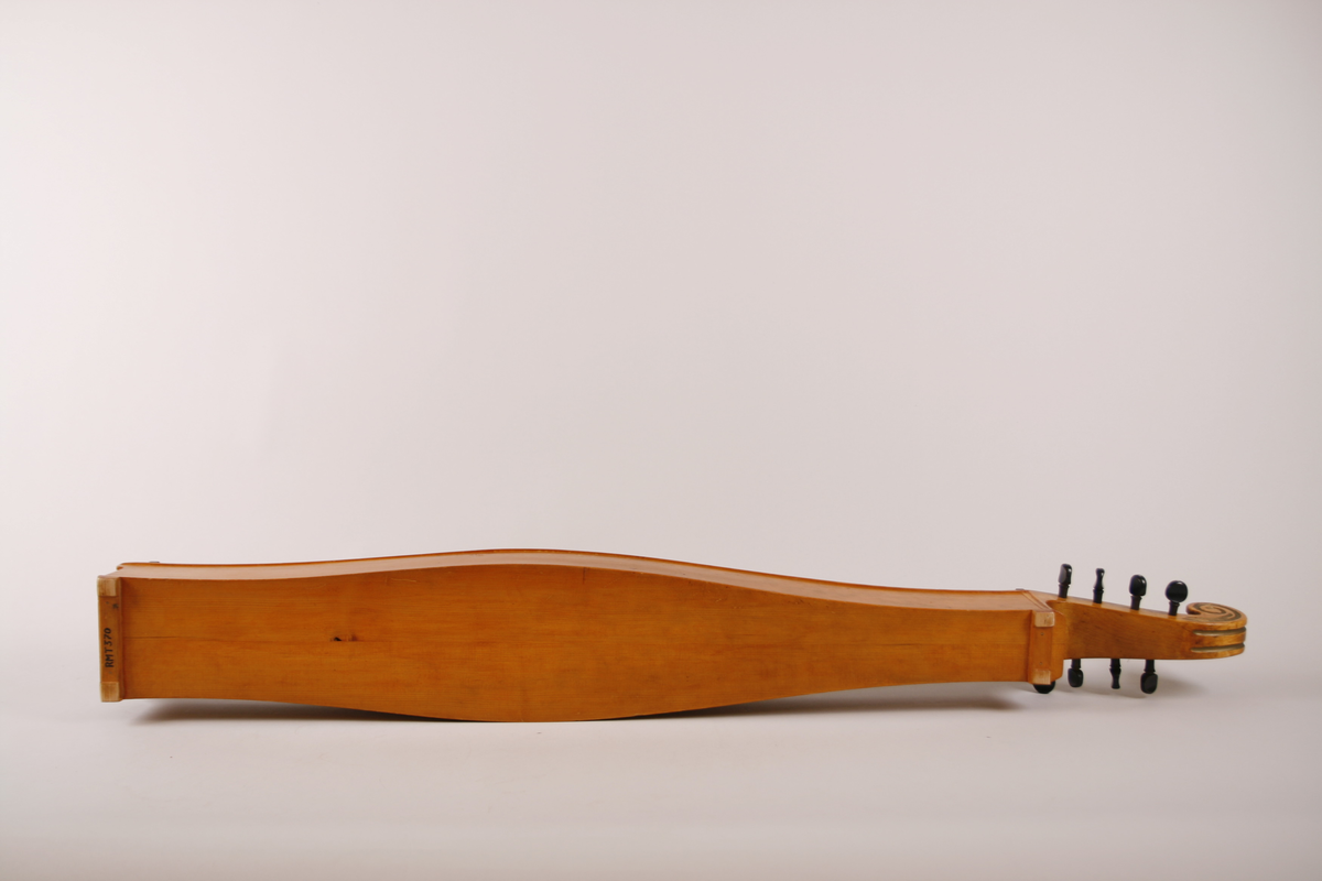 Lang, smal, buket korpus av gran. Skruekasse og hode i ett stykke. Hode i form av en snekke der profilene er dekorert med bronsemaling. Sortmalte stemmeskruer med perlemorsøye på kanten av hodet. Rundt lydhull. Tusjborder langs lokkanten og rundt lydhullet, samt blomstreranke i tusj nederst på lokket.
1 melodistreng og 7 resonansstrenger. Under melodistrengen 14 pålimte noter i ibenholt (spor etter fler noter enten flyttet eler fjærnet). Stopper mangler. 3 pyamider mangler. Strengeleder i form av skruer med insaget hakk. 
Strengene er festet med anhengsskruer direkte bak stolen på lokket. Skruene (8 st) er festet gjennom lokket i nedre sarg
Instrumentet er usignert.