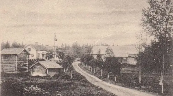 Svart/hvitt bilde av løbekksetra i Trysil: Vi ser en grusvei og på hver side av grusveien er det gårdshus. 