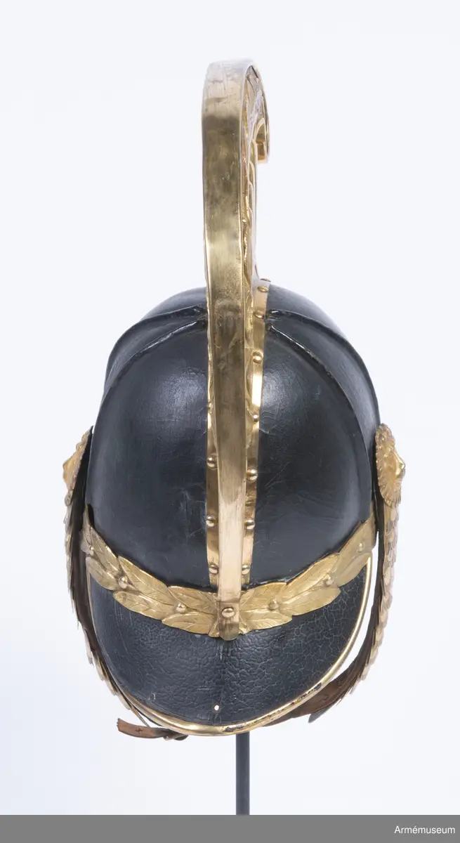 Kask med förgylld mässingskam.

Kasken är tillverkad av svartlackat tjockt läder som har pressats och formats till en hjälm.
Den består av två halvdelar med söm på mitten som döljs på utsidan av en mässingskam som löper från pannan till nacken. Kammen är dekorerad med lagerblad längst upp och avslutas i ett volut fram. Den sitter ihop med framskärmen/vapenplåten. Från kullen och ner löper två svarta ribbor på varje sida, troligen med stål inuti.
Kasken har välvd mässingsskärm fram i vilken den separat stansade vapenplåten är fastsatt, och nackskydd bak kantad med mässingslist. Vapenplåten består av vapensköld med tre kronor (Lilla Riksvapnet) inom en ordenskedja för Serafimerorden. Kring hjälmen i nacken löper ett beslag av mässing i form av en stiliserad lagerkrans med bär.
Hakremmen är klädd med flerflikiga dekorerade mässingsfjäll som överlappar varandra i gradvis minskande storlek, och är fäst i varje sida under en stor lejonmaskaron av mässing. Remmen är fodrad med svart sammet, och spänns ihop mitt fram med ett litet mässingsspänne. Flera fjäll saknas i vänster remhalva.
Kaskinredningen är av mörkbrunt skinn, fastsatt längs med Kaskens innerkant och bestående av klippta tungor med en mässingsöljettl i varje rundning, genom vilka kunde löpa ett band eller en rem som kunde justeras efter huvudstorlek.

Kammen saknar fäste för tagelliggare.