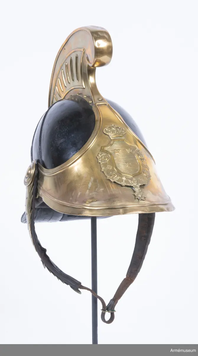 Lilla riksvapnet är pressat och fastsatt i plåten fram. Hela kasken är av en något lägre modell.
