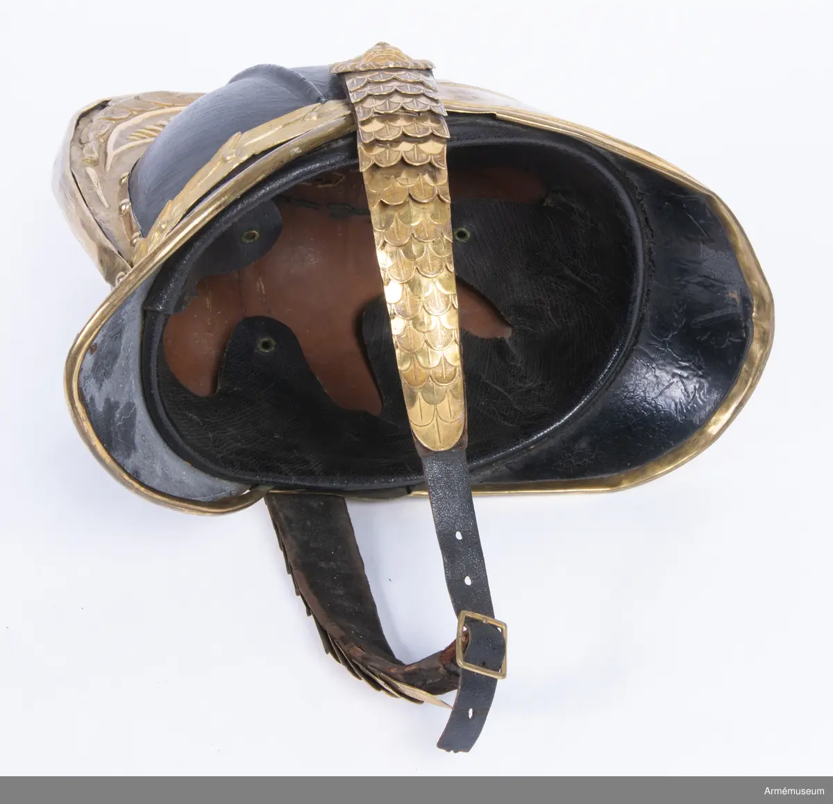 Kask med förgylld mässingskam.

Kasken är tillverkad av svartlackat tjockt läder som har pressats och formats till en hjälm.
Den består av två halvdelar med söm på mitten som döljs på utsidan av en mässingskam som löper från pannan till nacken. Kammen är dekorerad med lagerblad längst upp och avslutas i ett volut fram. Den sitter ihop med framskärmen/vapenplåten. Från kullen och ner löper två svarta ribbor på varje sida, troligen med stål inuti.
Kasken har välvd mässingsskärm fram i vilken den separat stansade vapenplåten är fastsatt, och nackskydd bak kantad med mässingslist. Vapenplåten består av vapensköld med tre kronor (Lilla Riksvapnet) inom en ordenskedja för Serafimerorden. Kring hjälmen i nacken löper ett beslag av mässing i form av en stiliserad lagerkrans med bär.
Hakremmen är klädd med flerflikiga dekorerade mässingsfjäll som överlappar varandra i gradvis minskande storlek, och är fäst i varje sida under en stor lejonmaskaron av mässing. Remmen är fodrad med svart sammet, och spänns ihop mitt fram med ett litet mässingsspänne. Flera fjäll saknas i vänster remhalva.
Kaskinredningen är av mörkbrunt skinn, fastsatt längs med Kaskens innerkant och bestående av klippta tungor med en mässingsöljettl i varje rundning, genom vilka kunde löpa ett band eller en rem som kunde justeras efter huvudstorlek.

Kammen saknar fäste för tagelliggare.