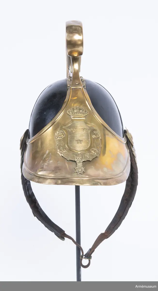 Lilla riksvapnet är pressat och fastsatt i plåten fram. Hela kasken är av en något lägre modell.