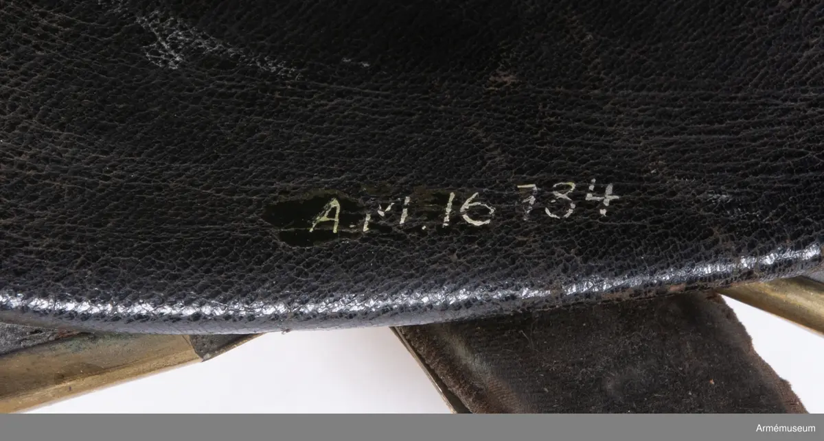 Kask med förgylld mässingskam.

Kasken är tillverkad av svartlackat tjockt läder som har pressats och formats till en hjälm.
Den består av två halvdelar med söm på mitten som döljs på utsidan av en mässingskam som löper från pannan till nacken. Kammen är dekorerad med lagerblad längst upp och avslutas i ett volut fram. Den sitter ihop med framskärmen/vapenplåten. Från kullen och ner löper två svarta ribbor på varje sida, troligen med stål inuti.
Kasken har välvd mässingsskärm fram i vilken den separat stansade vapenplåten är fastsatt, och nackskydd bak kantad med mässingslist. Vapenplåten består av vapensköld med tre kronor (Lilla Riksvapnet) inom en ordenskedja för Serafimerorden. Kring hjälmen i nacken löper ett beslag av mässing i form av en stiliserad lagerkrans med bär.
Hakremmen är klädd med flerflikiga dekorerade mässingsfjäll som överlappar varandra i gradvis minskande storlek, och är fäst i varje sida under en stor lejonmaskaron av mässing. Remmen är fodrad med svart sammet, och spänns ihop mitt fram med ett litet mässingsspänne. Flera fjäll saknas i vänster remhalva.
Kaskinredningen är av mörkbrunt skinn, fastsatt längs med Kaskens innerkant och bestående av klippta tungor med en mässingsöljettl i varje rundning, genom vilka kunde löpa ett band eller en rem som kunde justeras efter huvudstorlek.

Kammen saknar fäste för tagelliggare.