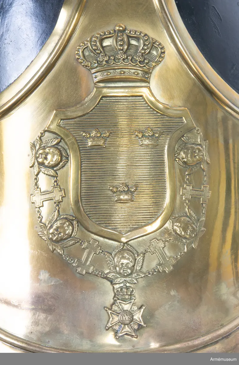 Lilla riksvapnet är pressat och fastsatt i plåten fram. Hela kasken är av en något lägre modell.