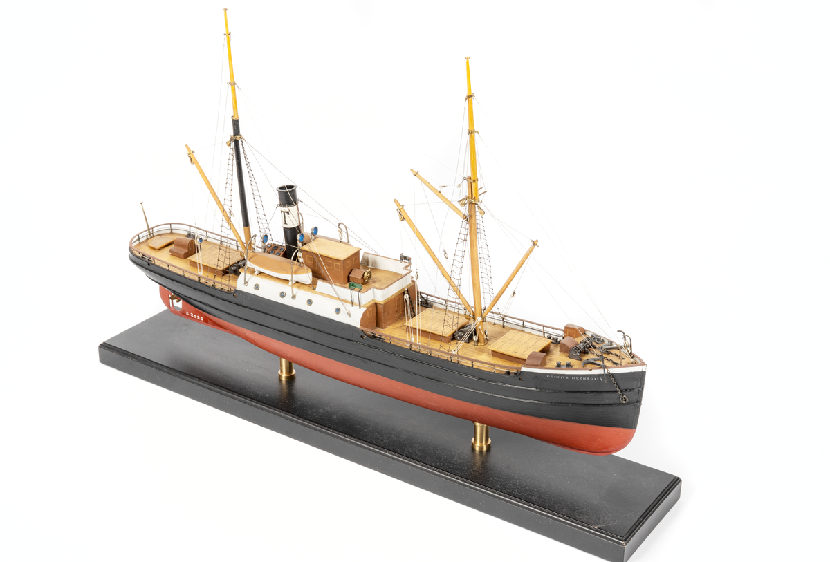 Fartygsmodell. Ångfartyget "CORFITZ BECK-FRIIS," Hel, i block av trä, fullt utrustad. Två master, tre lastbommar, en gaffel. Vitt skorstensbälte med svart T. Midskeppsbyggnad med runda vita sidor, öppen brygga, svart sida, röd botten.