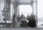 Foto av män och kvinnor som sitter på verandan till Borgsjö prästgård.