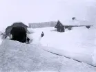 Foto av en snötäckt järnvägstunnel med män som står vid sidan om spåret. Text i album: 