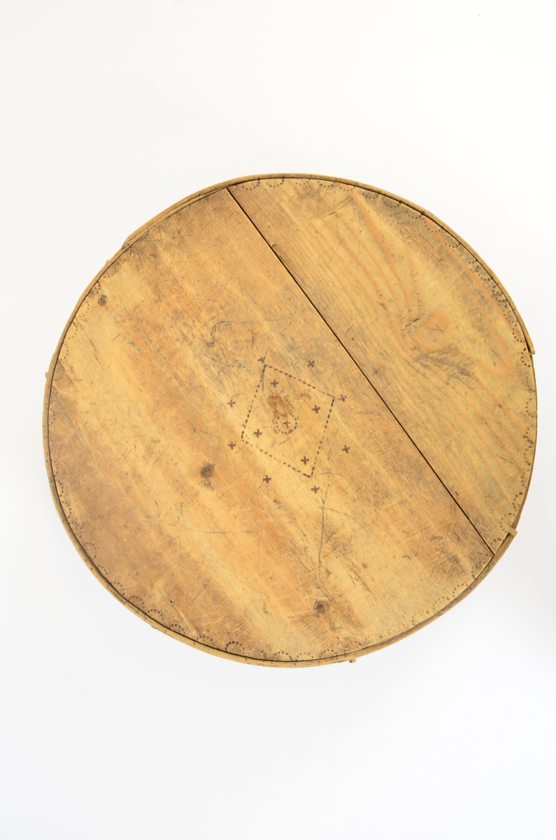 Gran. Sirkulær. Bunn og topp består av bord med spor langs kanten. Sidene, både i eske og lokk, utgjøres av bøyd spon, sydd sammen med tæger. Lokket er noe videre enn esken. Enkel sviornamentikk på innsiden av bunn og lokk, under bunnen og på sidene, rikere ornamentikk på lokkets overside. Sentralt sirkulært motiv, omgitt av fire kvadrater og fire rosetter. Buebord langs alle kanter.