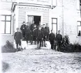 Foto av en grupp militärer som står vid en trappa till en byggnad. Text i album: 