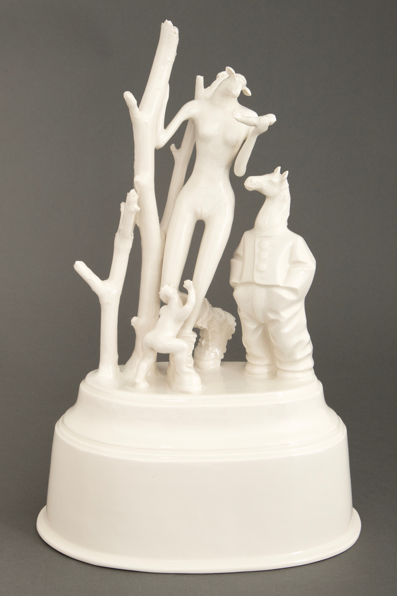 Objekt i hvitglasert porselen. På oval, hul sokkel står flere stiliserte figurer. Ytterst til høyre en figur med hestehode ikledd dress. I midten en figur med kvinnekropp og sauehode, kledd i kraftige støvler og med en avkuttet arm i ene hånden. Foran en mindre figur med hønsehode og bare en arm, vendt med ryggen mot. Ytterst til venstre to døde trær.