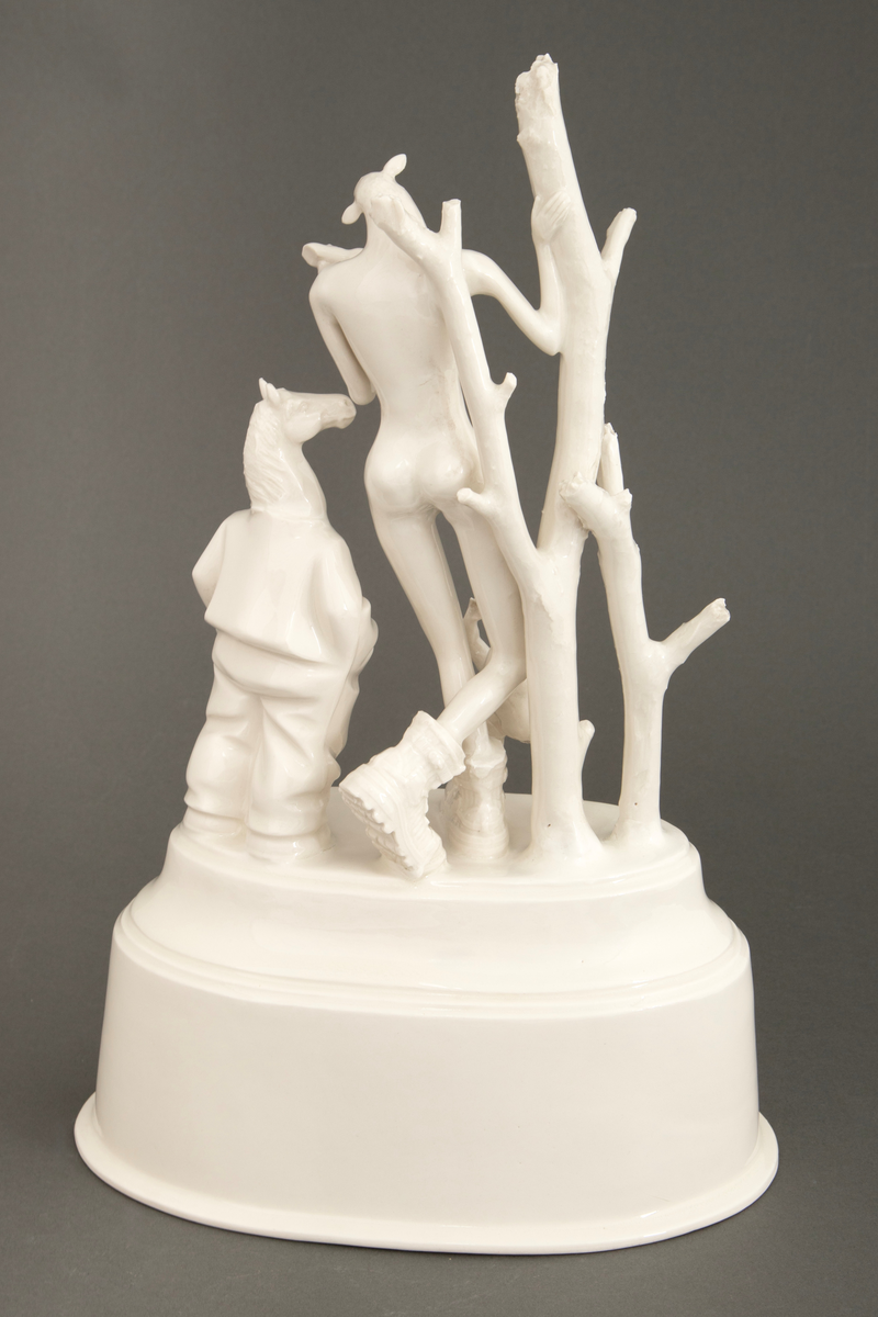 Objekt i hvitglasert porselen. På oval, hul sokkel står flere stiliserte figurer. Ytterst til høyre en figur med hestehode ikledd dress. I midten en figur med kvinnekropp og sauehode, kledd i kraftige støvler og med en avkuttet arm i ene hånden. Foran en mindre figur med hønsehode og bare en arm, vendt med ryggen mot. Ytterst til venstre to døde trær.