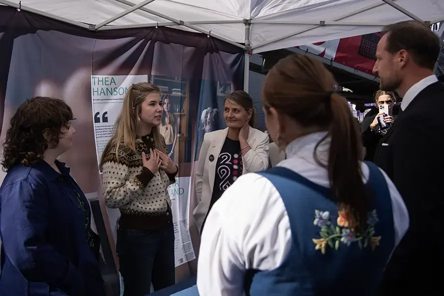 Tre kvinner på en stand som snakker med kronprinsen