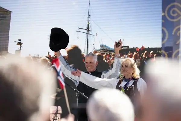 En kvinne og en mann som hilser til en folkemengde.