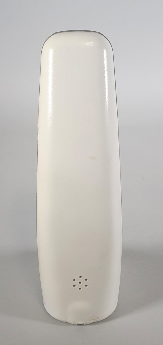 Hvit telefon med ledning, stående modell med tall-tastatur. Bred nederst, smalner inn mot toppen. Høytaler øverst. Knapp midt under for å avslutte samtalen. Logo for LIllehammer-OL og TBK over tastaturet.
