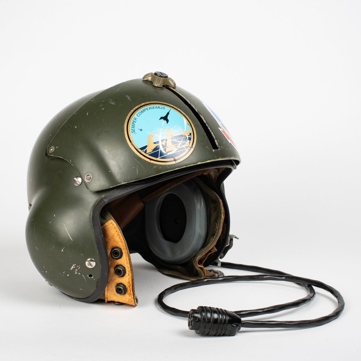 Flyghjälm SPH-4.
Grön flyghjälm med fast visirskydd av metall och tonat visir. Utksjutande form vid öronen för att ge plats för stora invändiga hörselkåpor. På vänster sida sitter en sladd för kommunikationsutrustningen, mikrofonen saknas. 
På visirskyddet sitter två runda klistermärken. Det högra med Forskningscentralens emblem med texten "SEMPER COMPERIEMUS", det vänstra är ett utbildningstecken för mörkerflygning inom marinflygning föreställande en svart fladdermus framför en blixt och en treudd samt text "SVARTA BARONERNA".