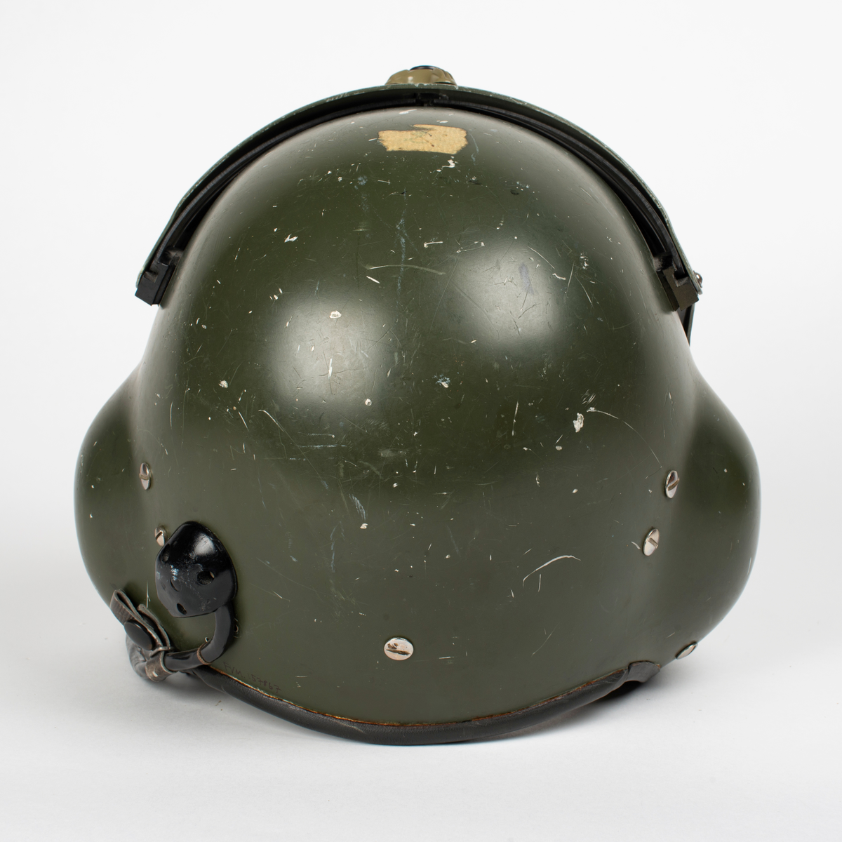 Flyghjälm SPH-4.
Grön flyghjälm med fast visirskydd av metall och tonat visir. Utksjutande form vid öronen för att ge plats för stora invändiga hörselkåpor. På vänster sida sitter en sladd för kommunikationsutrustningen, mikrofonen saknas. 
På visirskyddet sitter två runda klistermärken. Det högra med Forskningscentralens emblem med texten "SEMPER COMPERIEMUS", det vänstra är ett utbildningstecken för mörkerflygning inom marinflygning föreställande en svart fladdermus framför en blixt och en treudd samt text "SVARTA BARONERNA".